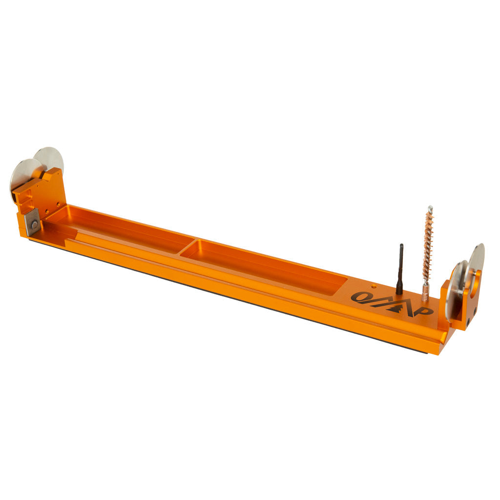 Orange anodized arrow spinner and squaring tool with two roller wheels and a small abrasive squaring disc, photographed against a white background.